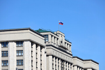 Parliament building in Moscow with Russian flag on background of clear blue sky. Facade of State...