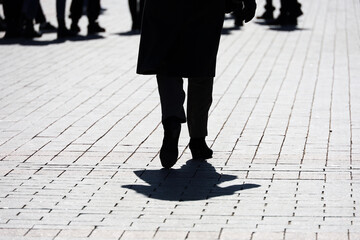 Silhouette and shadow of woman walking on a city street on crowd of people background. Concept of...