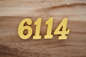 Golden Arabic numerals on a real brown and white wooden floor number 6114