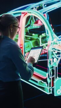 Vertical Screen. Innovative Green Energy Startup: Female Engineer Designing Electric Car Using Tablet Computer and Big Wall Screen to Analyse Prototype. Concept for Sustainable Carbon Neutral Vehicle