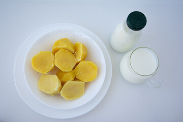 Vegan plant based milk in cup and bottle. Alternative potato milk and boiled potatoes in plate on...