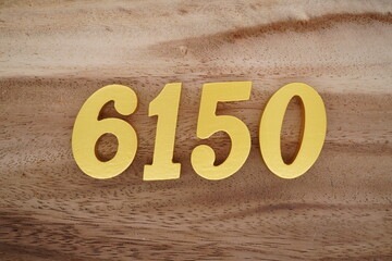 Golden Arabic numerals on a real brown and white wooden floor number 6150