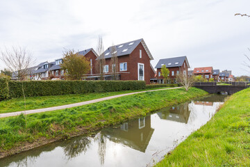 Fototapeta na wymiar Modern newly build family houses along canal in Kortenoord in Wageningen, Gelderland in The Netherlands