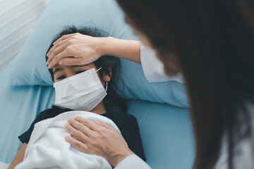 Asian woman pediatrician doctor put hand on chest for exam a little girl patient and heck heart lungs of kid, Good family doctor visiting child at home, Healthcare and medicine for childhood concept.