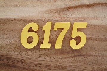 Golden Arabic numerals on a real brown and white wooden floor number 6175