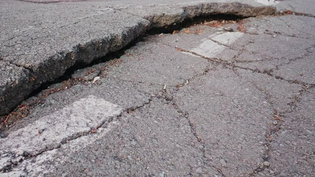 Close-up of deep crack that destroyed the highway next to the road markings, gap on the old highway, the consequences of man-made or natural disaster.
