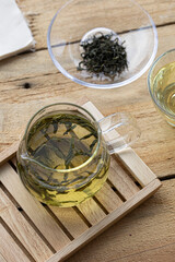glass cup of green tea and teapot isolated on wooden background.