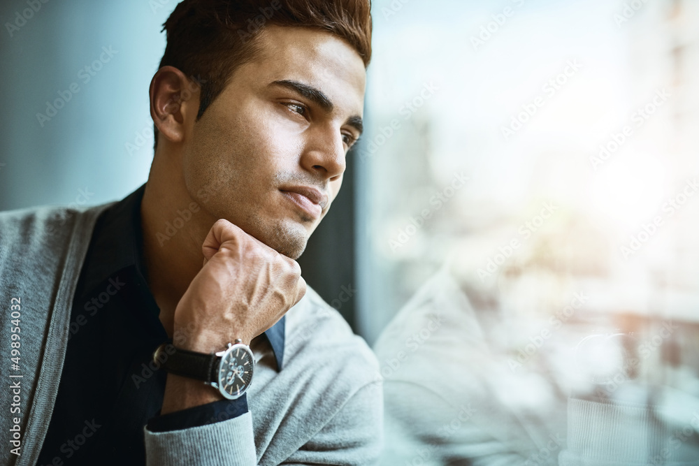 Sticker Who knows where success will lead him to next. Shot of a young businessman looking thoughtfully out the window in an office.