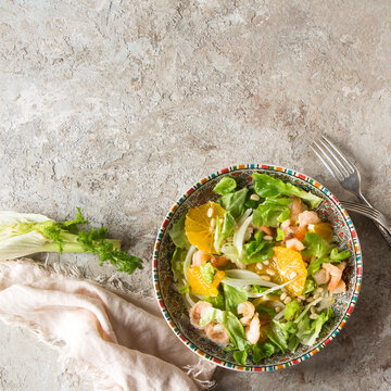 plate with salad with fennel, orange and shrimp on a light table