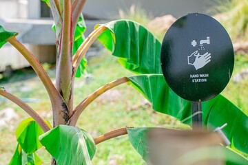 Hand wash station. Hand wash sign in resort with a banana tree in the outdoor garden.  