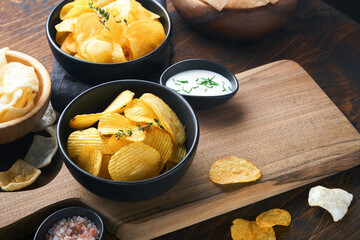 Potato corrugatedchips. Fast food. Crispy potato chips ceramic black bowl with sour cream sauce and...
