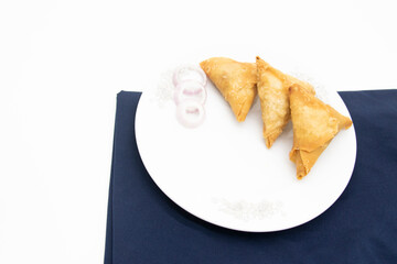 Samosa in a plate with onion isolated on white background