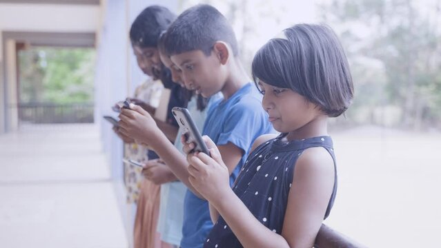 Group of kids busy using mobile phone at school corridor - concept of socil media, smartphone technology and gaming addiction