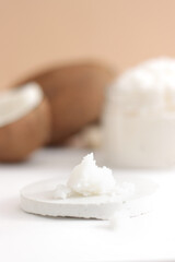 Scattered scrub with jar with coconut on white and brown background. Home spa treatment concept, organic cosmetic. Vertical photo