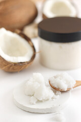 Fototapeta na wymiar scrub in wood spoon with jar coconut on white background. Home spa treatment concept, organic cosmetic. Vertical photo
