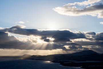 The rays of the setting sun through the clouds over the ocean