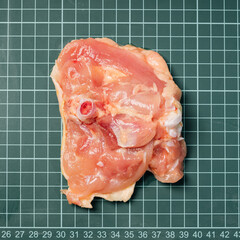 Raw chicken thigh with skin, boneless, for cooking on wooden cutting board.Chicken thigh meat on a...