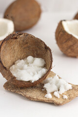 Scattered scrub in coconut on white background. Home spa treatment concept, organic cosmetic. Vertical photo