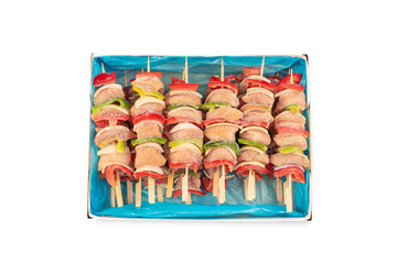 skewers of raw meat and vegetables.Frozen pieces of chicken skewers .Skewers with pieces of raw meat, red, yellow and green bell pepper, on white background. Close-up.