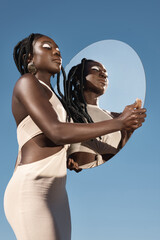 Self reflection brings self acceptance. Shot of an attractive young woman holding a mirror with her...