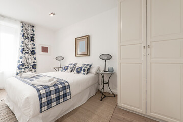bedroom with double bed with rolled towels and built-in wardrobe with white wooden doors, cushions,...