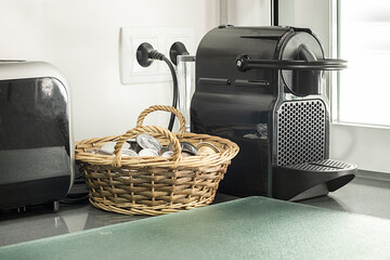 Corner of a kitchen with a capsule coffee machine next to a toaster on a dark gray stone worktop