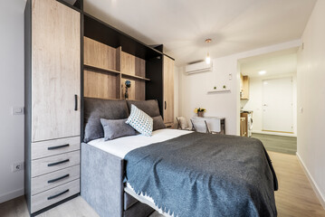 Extended pull-out bed with cushions, blankets and white bedding in short-term rental studio...