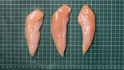 Fresh chicken inner fillet on a linear board. Raw chicken fillet meat without skin without bone,...