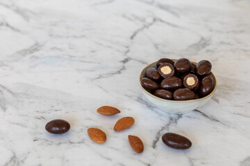 Almonds coated with dark chocolate glaze. Chocolate nut sweet snack in bowl.