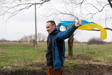 man with the flag of Ukraine near the burnt tree