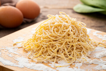 Close up Chinese egg noodle on wooden board,Thin yellow noodles covered by flour on wood table