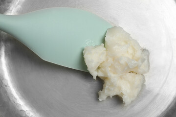 Frying pan with coconut oil and spatula, top view