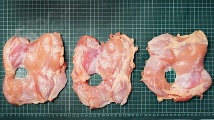 Raw skinless boneless chicken thigh, for cooking.Chicken thigh,leg meat on a line board.