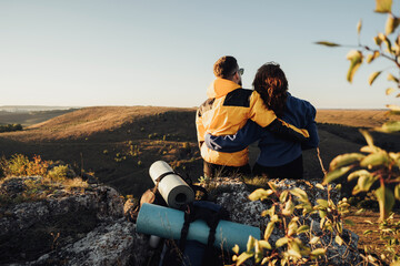 Back View of Traveler Couple Hugging and Sitting on the Edge of Hill During Sunset, Travel Couple Enjoy Their Hiking Trip on Top of the Hill