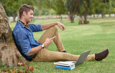 Better than any library. Shot of a handsome young man studying in the park with a laptop.