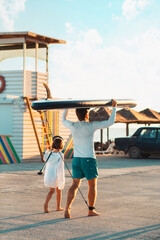Summer family activity. Father and daughter are walking along the beach. Man holding a sup board....