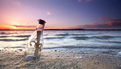Foto op Plexiglas romantic sunset at the beach with bottle with a message © Jenny Sturm