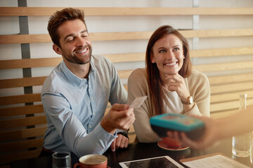 Bill it on my card. Shot of a young couple making a credit card payment in a cafe.