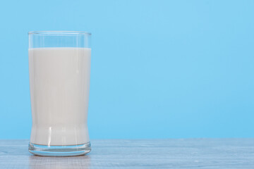 World Milk Day, A glass of white milk isolated on a wooden desk and blue background, close up. Happy Milk Day. Dairy product concept, copy space on right for design, nobody, World Milk Day 1 June
