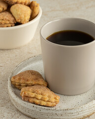 Сup of black coffee with cottage layer cookies with sugar and cinnamon, white ceramic bowl with cookies