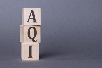 AQI Abbreviation of air quality index text on wooden cubes on dark gray wall background.