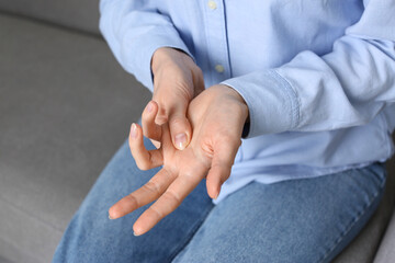 Woman suffering from trigger finger on sofa, closeup