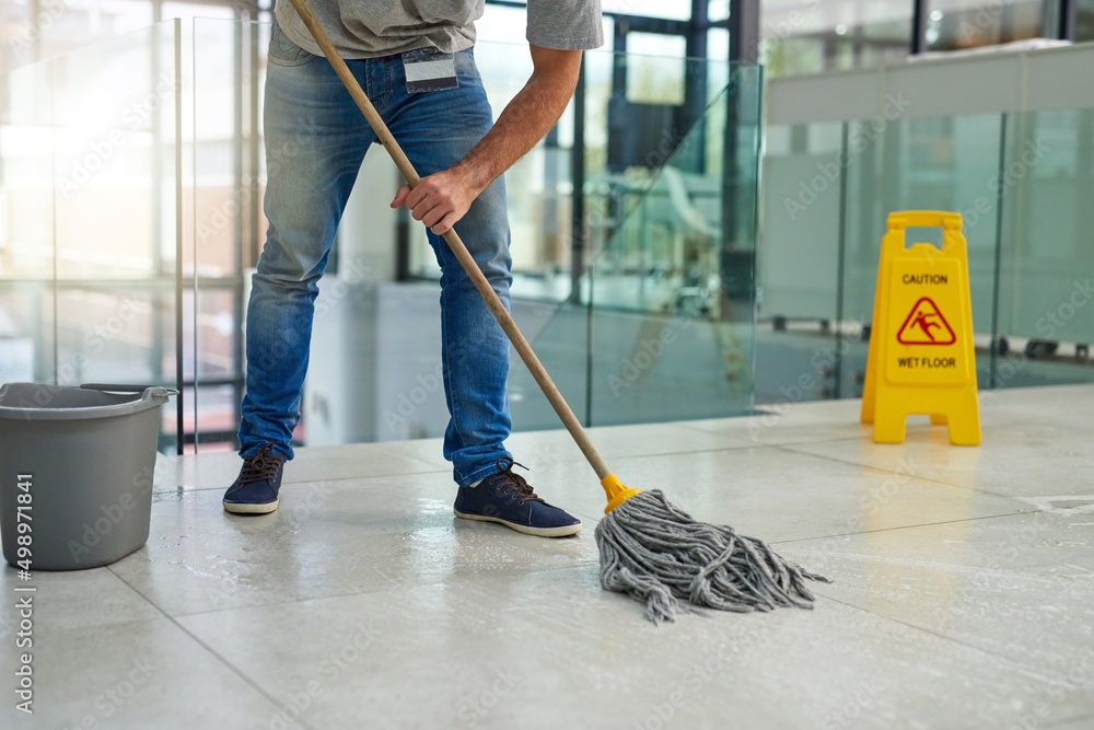 Poster hell leave that floor spotless. shot of an unrecognizable man mopping the office floor.