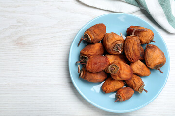 Plate with tasty dried persimmon fruits on white wooden table, flat lay. Space for text