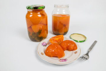 Fototapeta na wymiar jars of pickled tomatoes and tomatoes in a plate on white.
