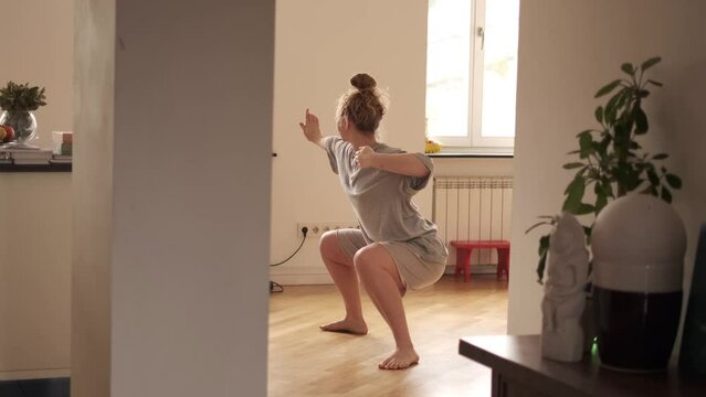 Woman practicing qigong at her cozy apartment