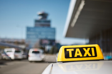 Selective focus on taxi sign on roof of car against airport terminal. .