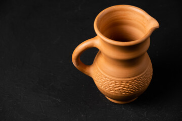 clay jug on a dark background with earthenware