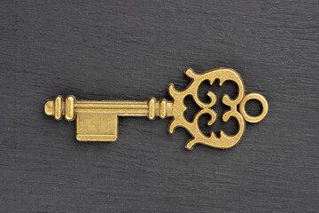 Bronze vintage antique key on black wooden background. Concept of antiques