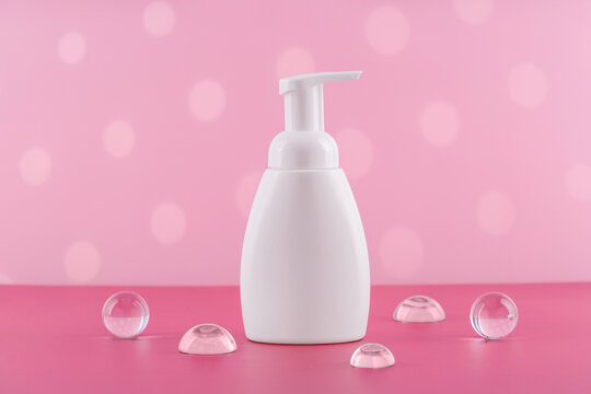 Bath soap white cosmetic bottle mockup on pink background with stylish props. Body care foam product or lotion packaging. Plastic cosmetics tube front view mock up. Body hygiene cream